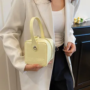Detail of yellow patent leather box bag with MAUDAI BEAR embossing and metal zipper