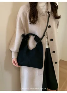 Bolso de ante negro minimalista con detalle de asa anudada combinado con un abrigo beige