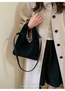 Bolso hobo minimalista de ante negro combinado con un abrigo beige sofisticado