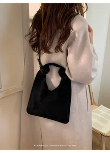 Foto street style de un bolso tote de ante negro combinado con un abrigo beige largo