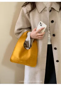 Detalle de bolso hobo de ante amarillo combinado con abrigo beige minimalista