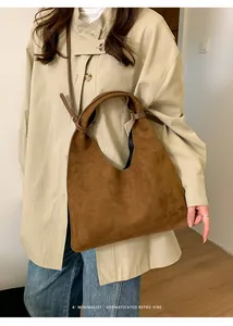 Detalle del bolso tote de ante marrón con una correa ancha decorativa con nudo suave