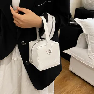 Close-up of a white box-shaped bag featuring the MAUDAI BEAR logo and silver metal clasp