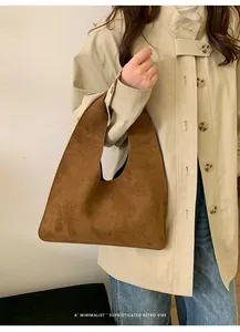 Detalle de bolso hobo de ante marrón combinado con una gabardina beige retro chic