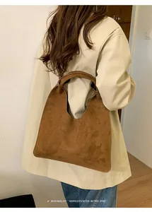 Bolso tote de ante marrón al hombro que muestra su gran capacidad y estilo retro minimalista