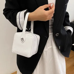 Detailed view of a white patent leather square handbag with embossed brand text details