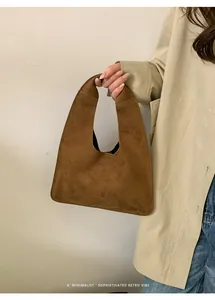 Primer plano del bolso tote de ante marrón oscuro con diseño trapezoidal y asa integrada