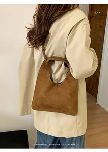 Bolso de ante marrón lucido por modelo, mostrando detalles de la correa y diseño minimalista