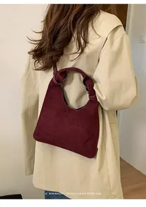 Primer plano de bolso tote de ante burdeos con asa anudada y estilo retro minimalista