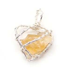 Vista macro de un colgante artesanal de cristal amarillo envuelto en alambre de plata