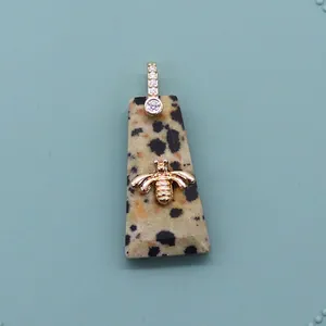 Macro detail of trapezoid natural stone pendant with golden bee and zircon bail