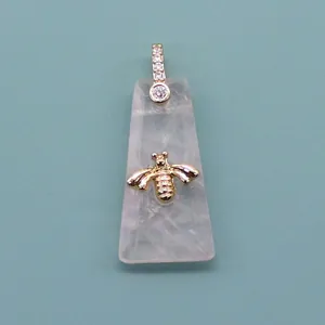 Macro detail of trapezoid rose quartz pendant featuring a gold bee and pavé zircon clasp