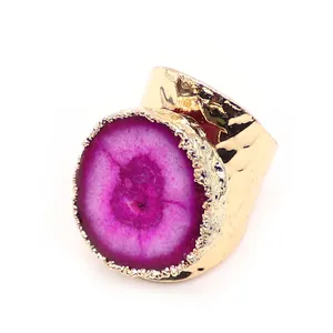 Primer plano de anillo de ágata rosa con banda dorada martillada y diseño ajustable