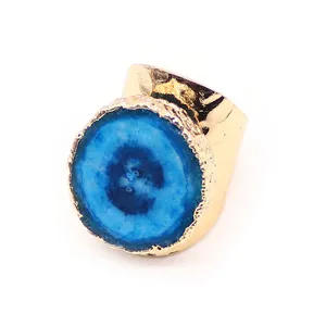 Detalle de anillo ancho de oro martillado con piedra de ágata druzy azul en fondo blanco