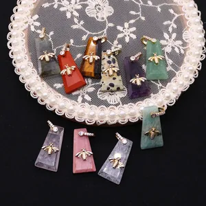 Trapezoid natural stone pendants with golden bee and zircon-encrusted bail on lace pad