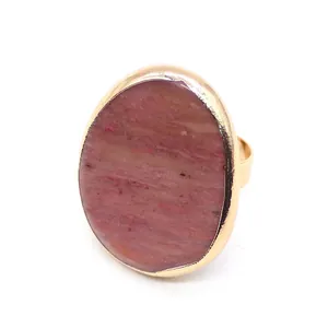 Detail of an adjustable gold ring with oval pink-brown textured agate stone