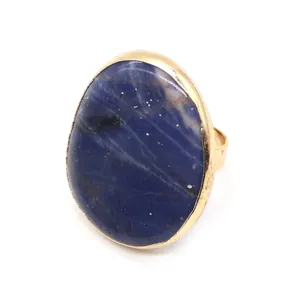 Macro view of oval natural blue sodalite stone ring with gold plated setting and textures