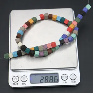 Macro shot of colorful cubic lava stone beads being weighed on a digital scale