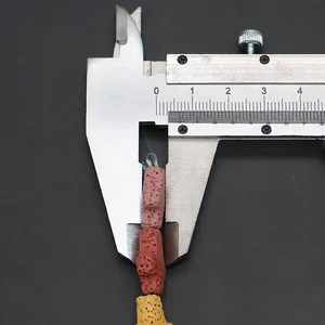 Mesure de la taille d'une perle en pierre de lave colorée avec un pied à coulisse
