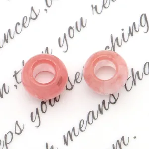 Dettaglio macro di due perle di agata rosa traslucida con fori grandi per gioielli DIY