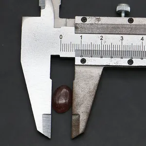 Macro-opname van een 12mm ovale rode agaat gemeten met een metalen schuifmaat tool