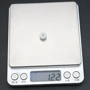 Macro di una perla in resina bianca su una bilancia digitale con peso di 1,22 g
