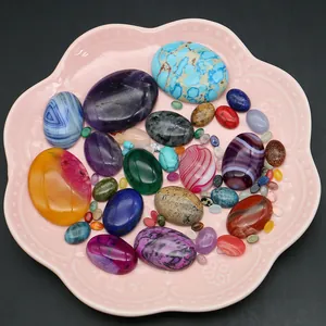 Verscheidenheid aan gepolijste ovale natuursteen cabochons in een roze bakje op zwart