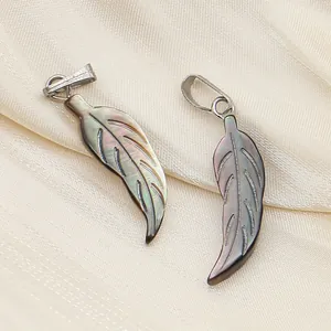 Détails macro de pendentifs en nacre noire sculptés en feuille sur un tissu en soie dorée