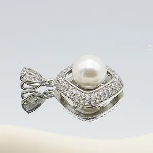 Macro shot of silver square pendant with pearl center and diamond-encrusted frame