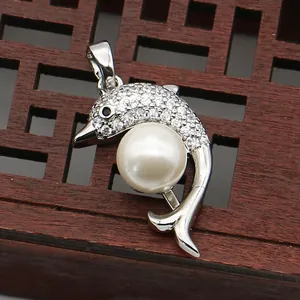 Detailed shot of dolphin-shaped silver pendant with white pearl and sparkling crystals