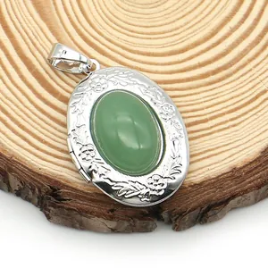 Detail of floral engraved oval locket pendant featuring a green stone inlay on wood