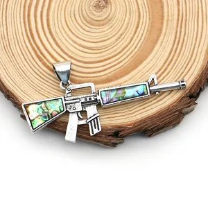 Macro de pendentif fusil argenté avec incrustation d'abalone sur fond de bois
