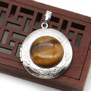 Close-up of vintage silver locket with tiger eye stone and floral relief on a wooden box