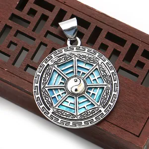 Macro detail of silver Tai Chi Bagua shell pendant with blue enamel and fret patterns