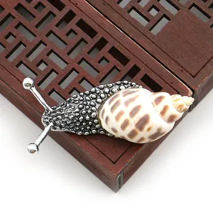 Detalle macro de broche de caracol de mar natural con textura de metal plateado en madera