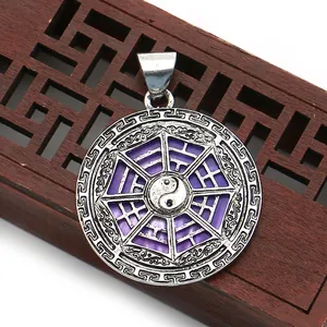Close-up of silver-plated purple shell Tai Chi Bagua pendant on a wooden background