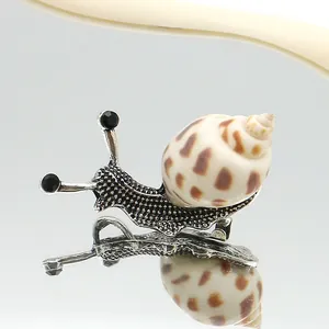 Detalle macro de broche de caracol con concha natural y textura de metal plateado