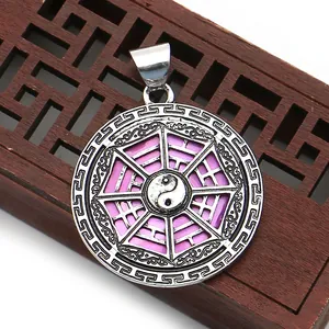 Macro shot of Yin Yang pendant with pink Ba Gua symbols and Greek key border design