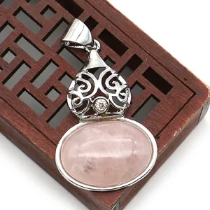 Macro shot of oval pink quartz pendant with intricate silver metal floral filigree detail