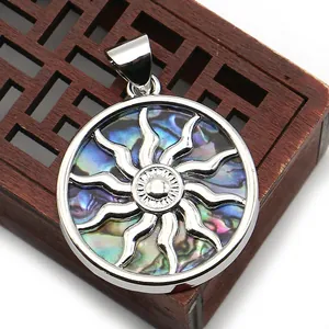Macro shot of circular abalone shell pendant with sunburst motif on a wooden box