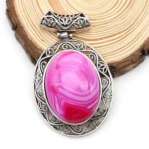 Detailed view of pink agate oval pendant with vintage hollow metal frame on wood