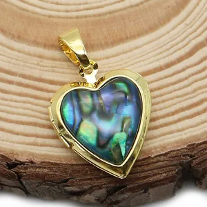 Macro di medaglione a cuore dorato con inserto in conchiglia di abalone su legno