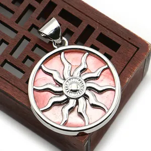 Detailed view of round shell pendant with silver sun totem and pink center stone