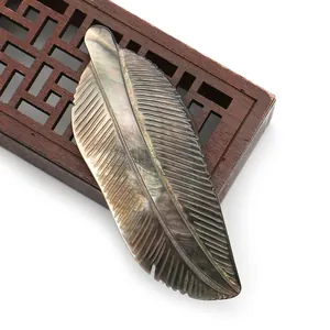 Macro detail of hand-carved feather shell pendant with natural iridescent pearl luster