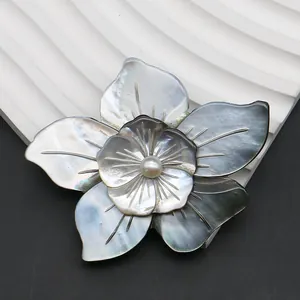 Natural black shell flower brooch with pearl center on white wave textured stand
