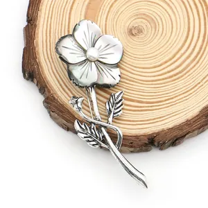 Detailed view of flower brooch with natural shell petals and pearl on a wood slice