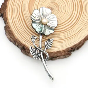 Macro detail of French shell flower brooch with pearl center on wood texture