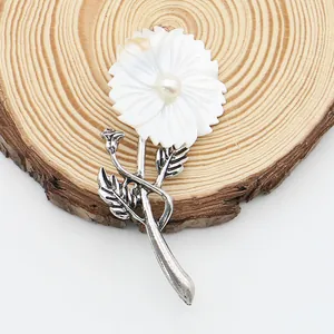 Macro detail of natural shell flower brooch with pearl center and vintage silver leaf