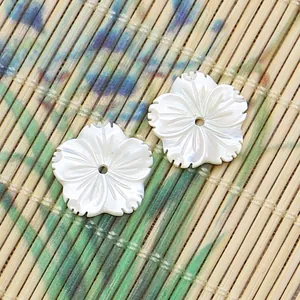 Vue macro de perles de fleurs en nacre blanche sculptées à la main sur un tapis en bambou
