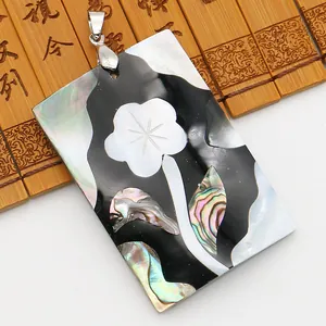 Détail macro d'un pendentif en nacre rectangulaire avec une fleur sculptée sur bambou